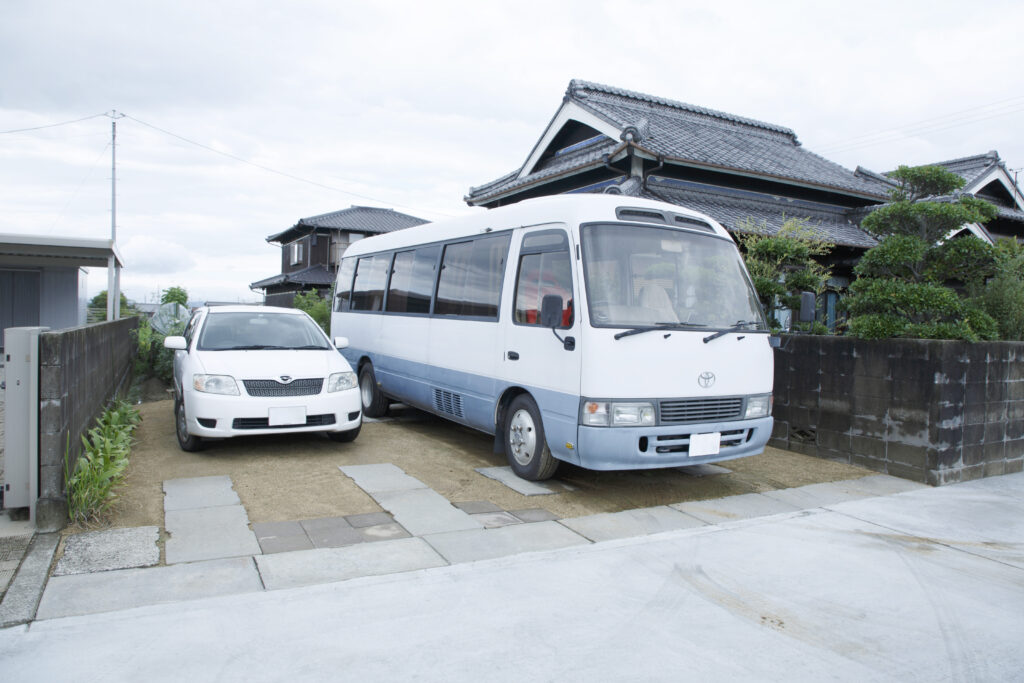 住宅前の駐車スペースに停まる、乗用車とひぽぽばす